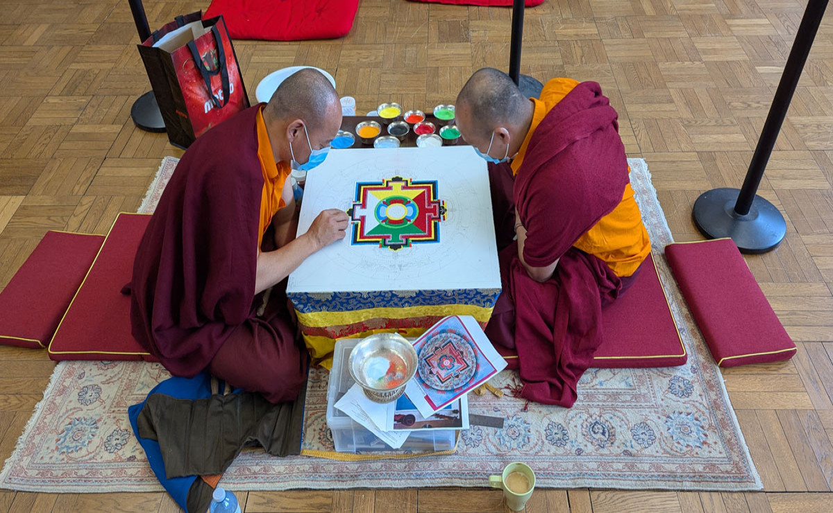 Tibetan monks from the Palyul Pema Mani Center create a sand mandala at Emmanuel College, marking 10 years of the Buddhist focus in the MPS program.