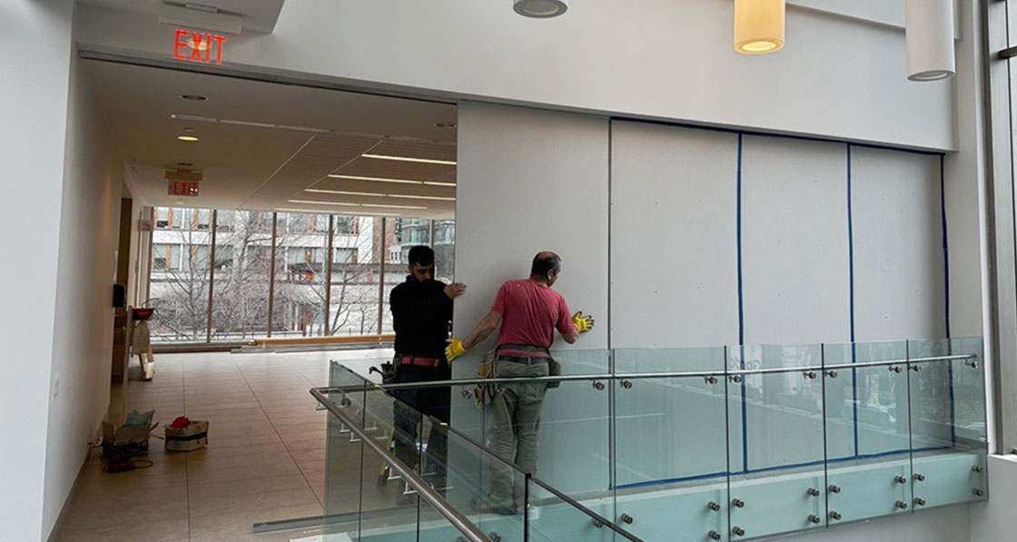 Construction workers mounting hoardin in Goldring Student Centre, March 2024.