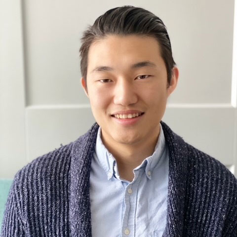 Sam Kang, wearing a blue dress shirt and blue cardigan. 