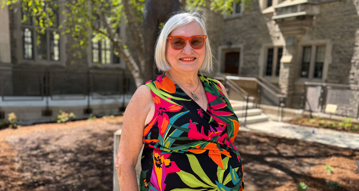 Judith Russo poses for the camera, smiliing, in the Indigenous Healing Garden at Emmanuel College.