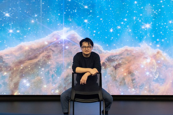 Peter Ma Peter Ma sitting in a chair in front of a screen featuring stars and space.